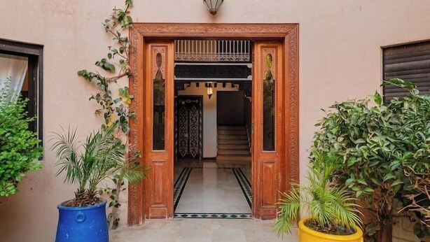 A building entrance with a sign, a staircase, and potted plants. - Luxe Appt 2 CH Piscine & Parking (Marrakech)
