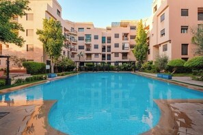 En swimmingpool omgivet af boligbygninger med flere etager og altaner.
