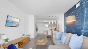 Una sala de estar moderna con un sofá, una mesa de centro y un televisor montado en la pared.