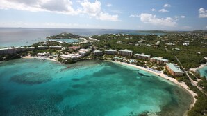 An aerial view of a coastal resort with multiple buildings, a beach, and clear turquoise waters. - Newly renovated luxurious 2 bedroom 2 1/2 bath beachfront condo. (St Thomas)