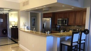 A modern kitchen with a central island, stainless steel appliances, and wooden cabinets. - Newly renovated luxurious 2 bedroom 2 1/2 bath beachfront condo. (St Thomas)
