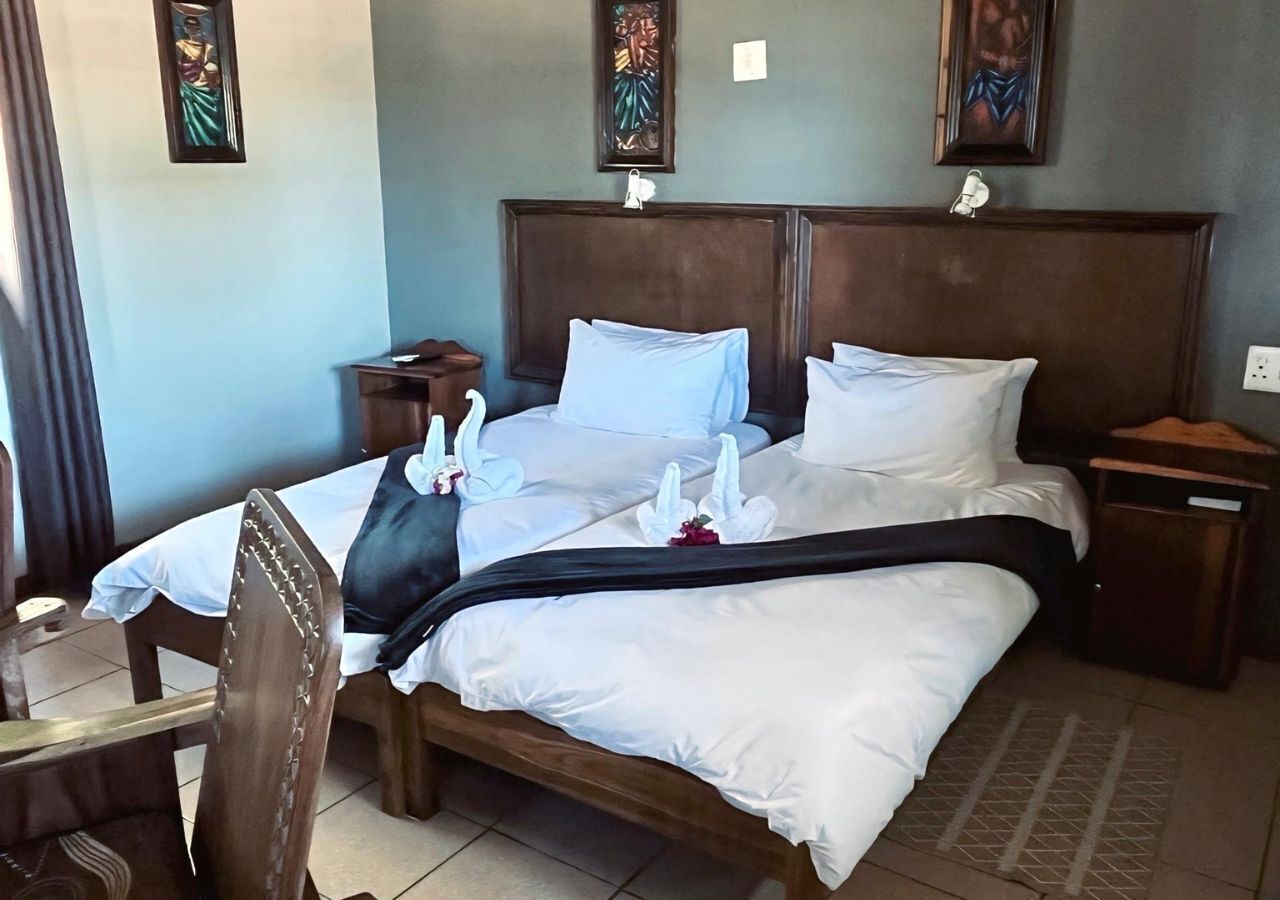 Een hotelkamer met een groot bed, houten hoofdbord en nachtkastje.