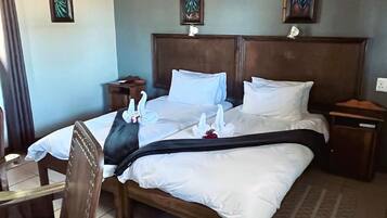 A hotel room with a large bed, wooden headboard, and a nightstand.