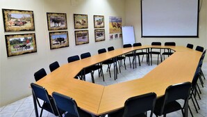 A conference room with a long table, chairs, a whiteboard, and framed pictures on the wall.