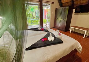 Habitación de hotel con dos camas, un banco y un televisor en la pared.