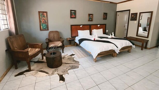 A bedroom with a large bed, two chairs, a wooden coffee table, and a rug.