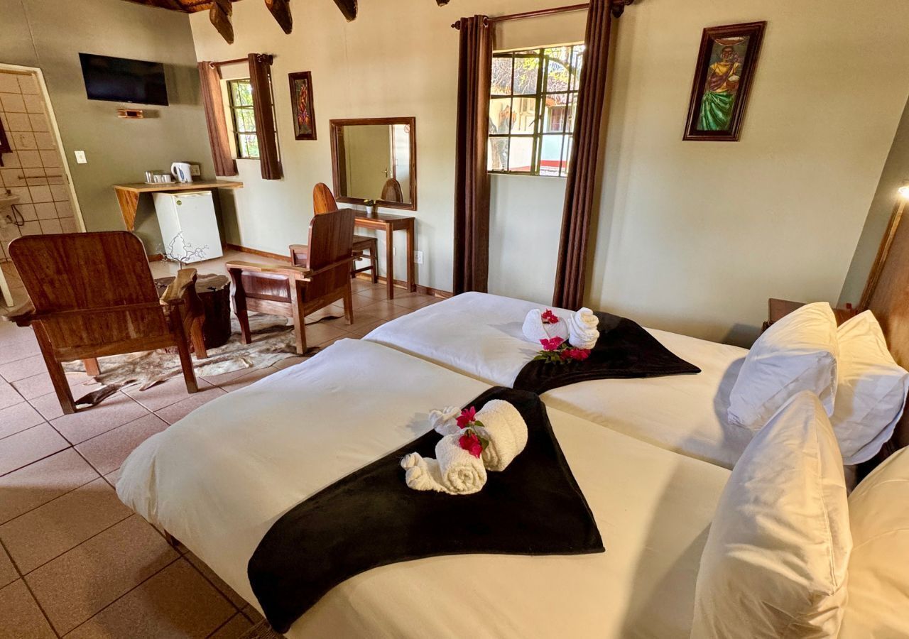 Hotellihuone, jossa on kaksi sänkyä, työpöytä, tuoli ja televisio.