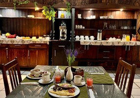 Desayuno preparado para dos personas, con platos de comida, tazas y una máquina de café.