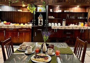 A breakfast setting with a table set for two, including plates of food, cups, and a coffee machine. - Ngandu Hotel - Rundu (Rundu)