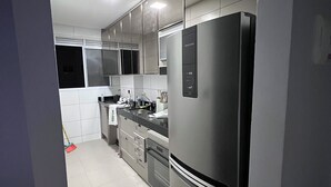Une cuisine moderne dotée d’appareils électroménagers en acier inoxydable, de meubles blancs et d’un dosseret carrelé.