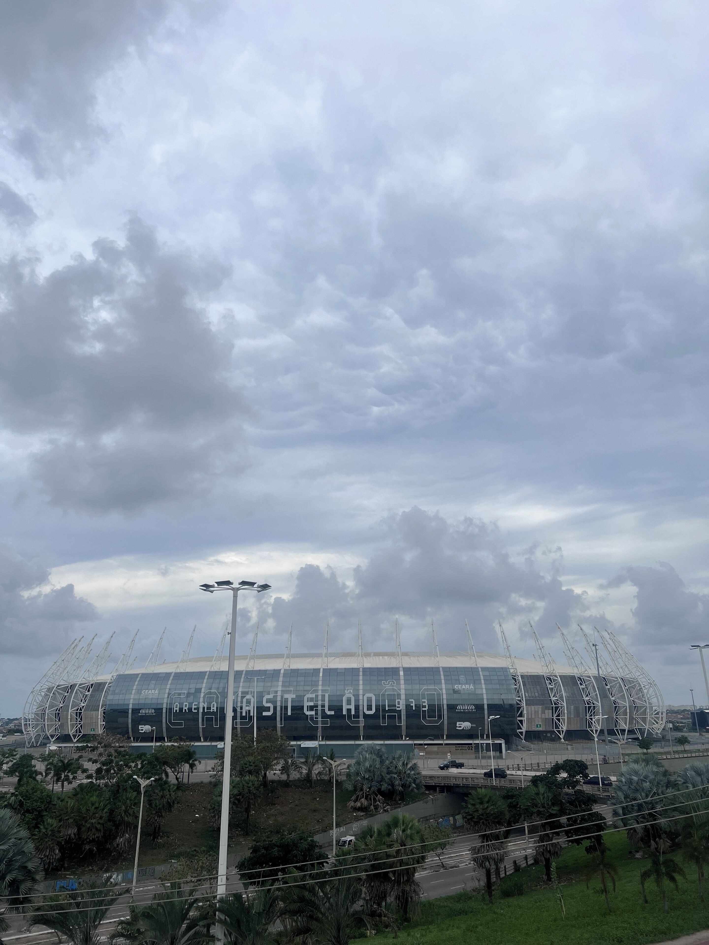 A stadium with a modern design, featuring a large, curved roof structure and multiple entry points.
