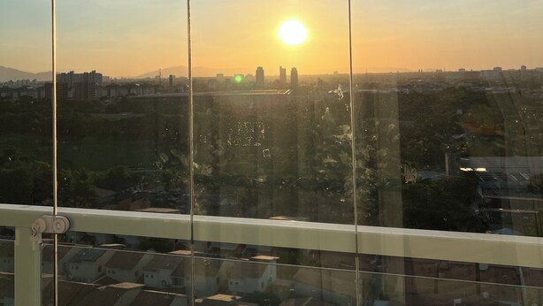 Une vue par la fenêtre, avec un ciel dégagé et le soleil se couchant à l’horizon.