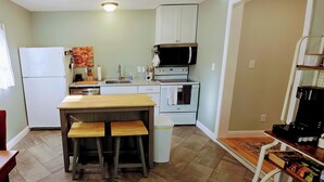 Una cocina compacta con refrigerador, estufa, microondas y un comedor con taburetes.