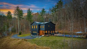 A modern two-story house with a dark exterior, large windows, and a swimming pool. - Woodstock Ridge / Hot Tub, Pool & Fire Pit (Woodstock)