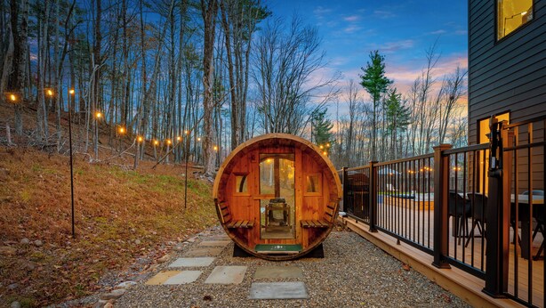 A wooden cabin with a circular entrance, surrounded by a gravel path and a wooden deck. - Woodstock Ridge / Hot Tub, Pool & Fire Pit (Woodstock)