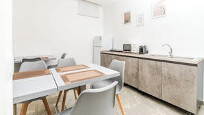 Cozinha moderna com ilha integrada, armários brancos e pia de aço inoxidável.