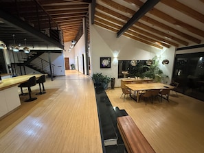 Una cocina amplia con una mesa de comedor de madera, taburetes de bar y una escalera que sube a un nivel superior.