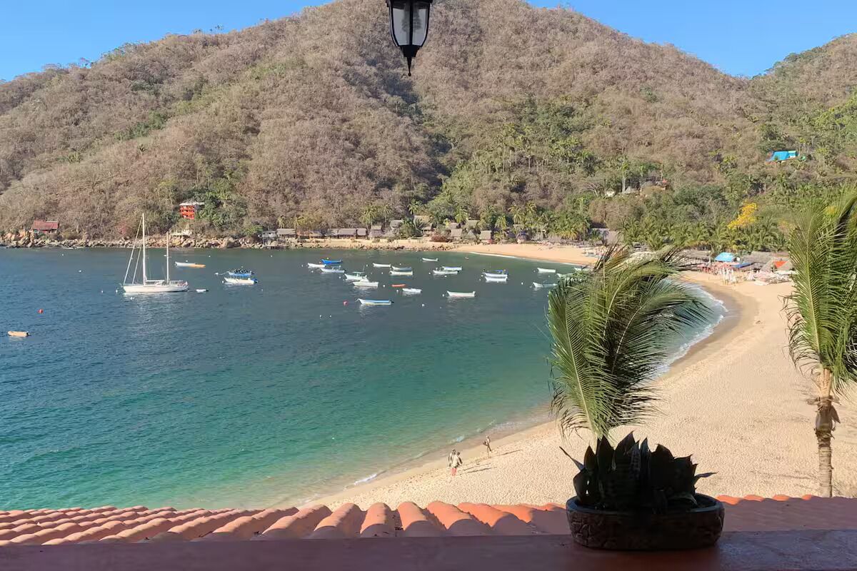 Une plage avec des bateaux, une montagne et un lampadaire.