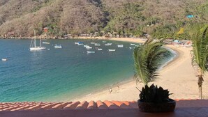 A beach with boats, a mountain, and a lamp post.