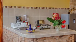 A kitchen with a tiled backsplash, a gas stove, a toaster, a coffee maker, and a decorative vase with flowers.