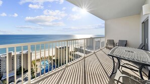 A balcony with a view of the ocean, a pool, and adjacent buildings. - Crystal Tower 1802: 2BR Condo (Gulf Shores)