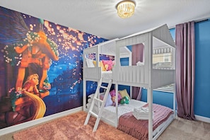 Habitación con literas, un mural, una escalera y una ventana con cortinas.