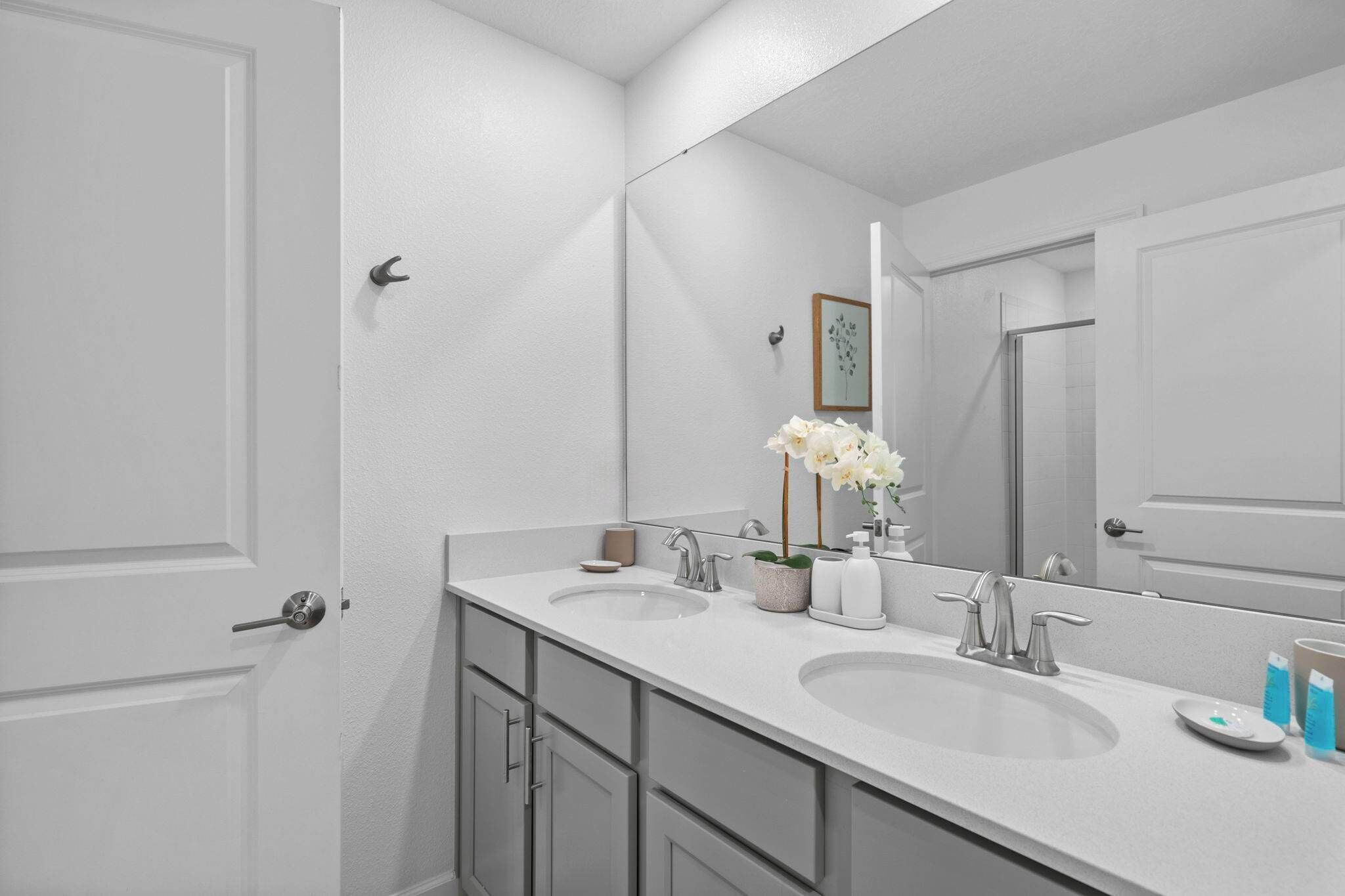 A bathroom with two sinks, a large mirror, and a door.