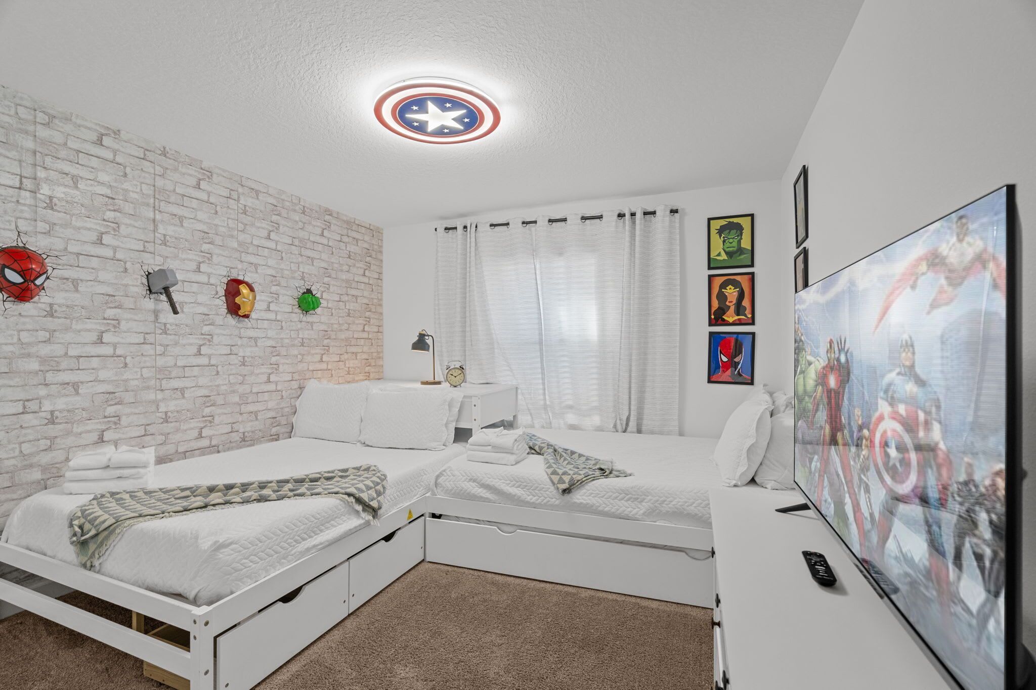 Ein Schlafzimmer mit zwei Betten, einem Fernseher und Dekor im Superhelden-Design.