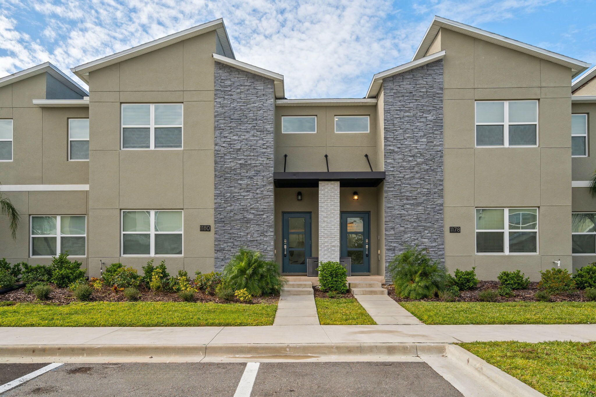 A modern building with a symmetrical facade, large windows, and a central entrance with a door and steps.