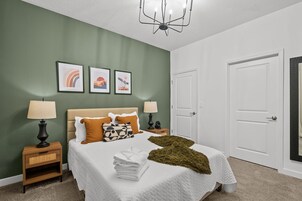 A bedroom with a bed, two nightstands, a chandelier, and a door.