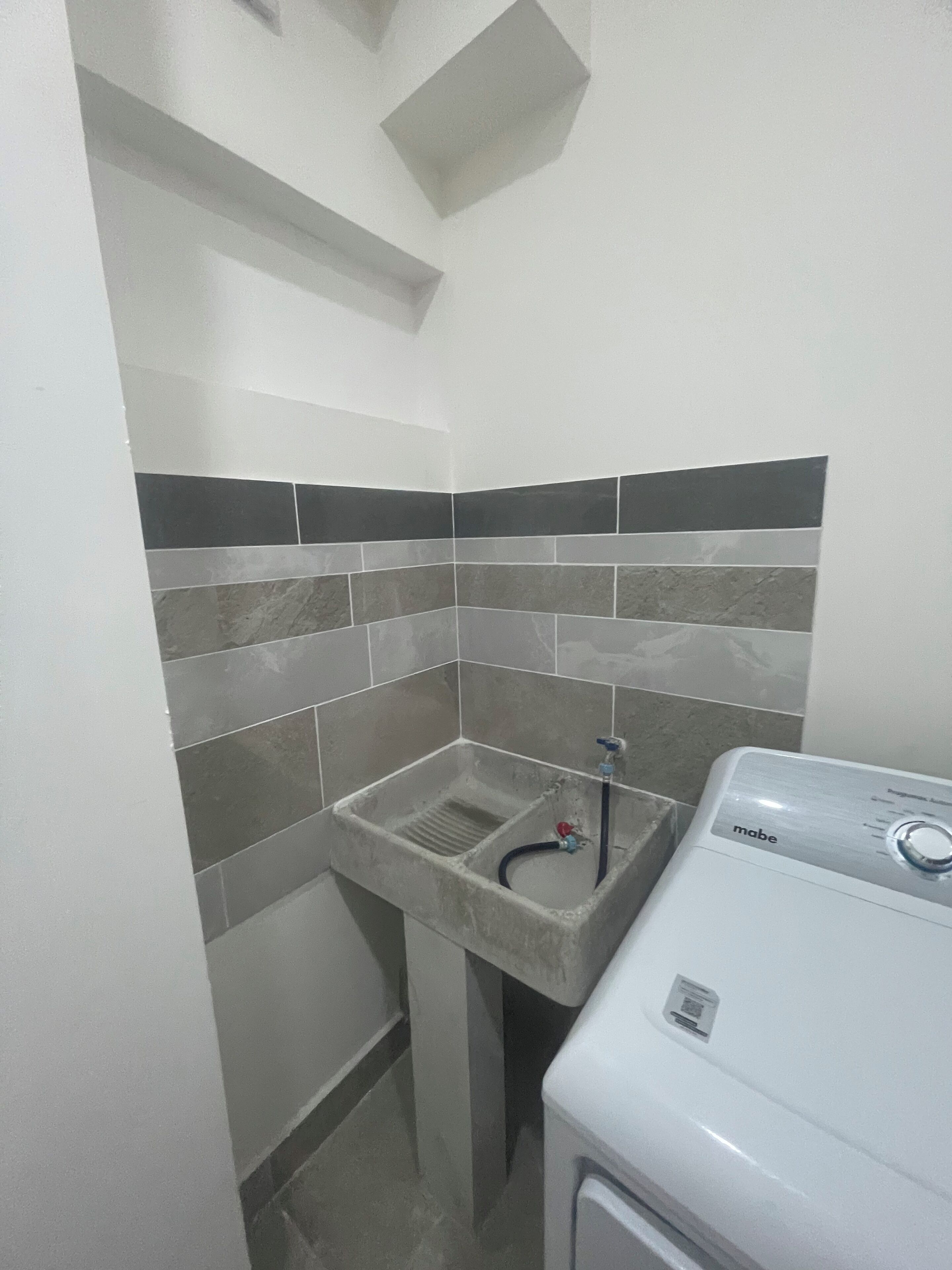 A small laundry area with a washing machine and a sink.