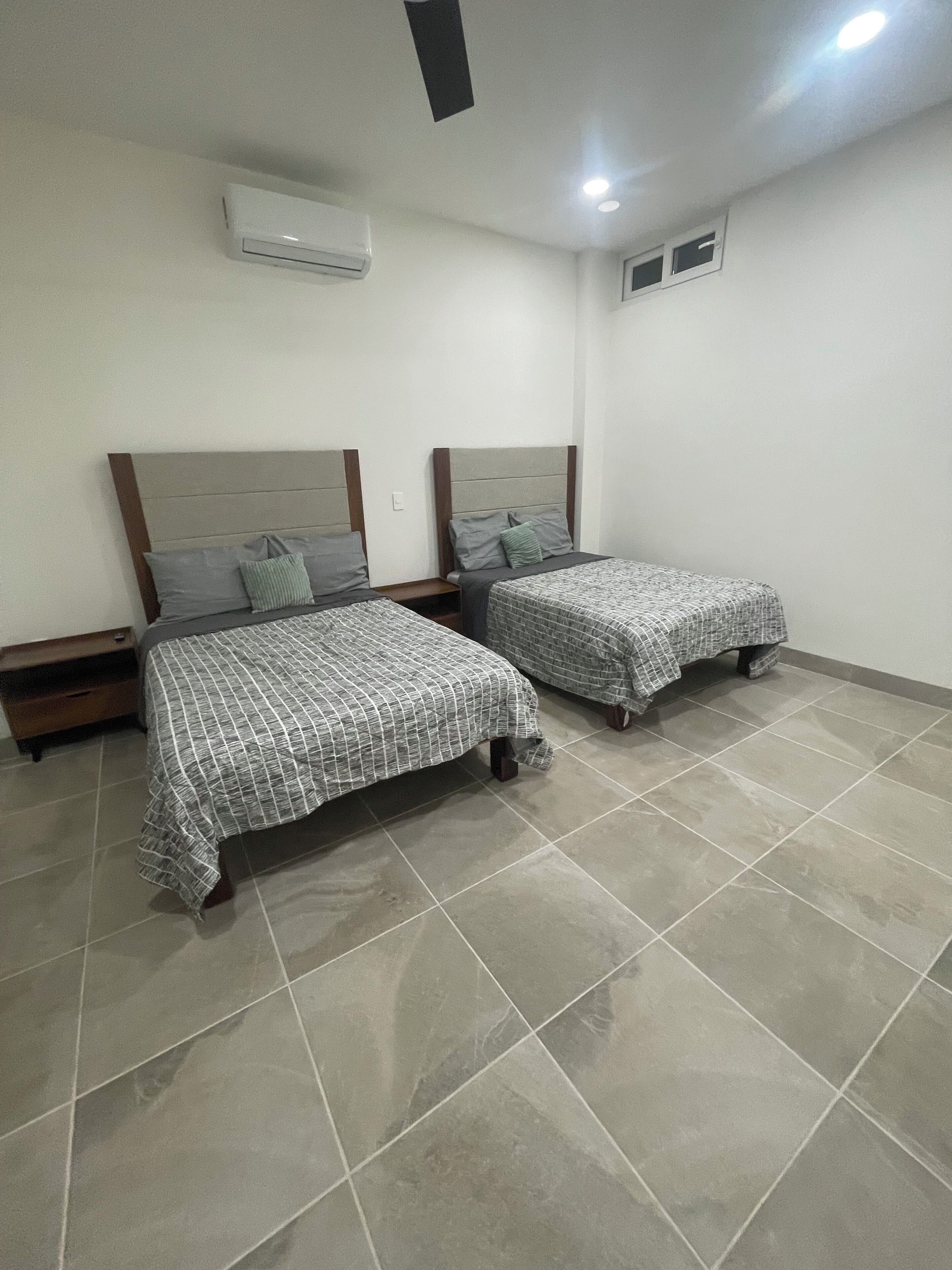 Een slaapkamer met twee bedden, een plafondventilator en een airconditioning.