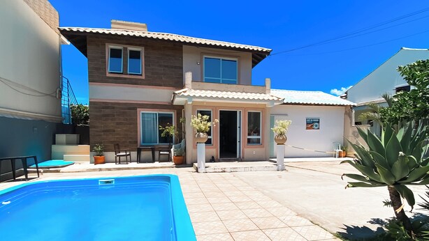 A two-story house with a swimming pool, outdoor seating, and potted plants. - Hostel Papai (Florianopolis)