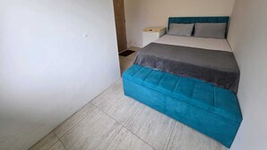 A small, narrow room with a bed, a nightstand, and a bench. - Hostel Papai (Florianopolis)