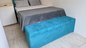 A bedroom with a bed, a bedside table, and a bench. - Hostel Papai (Florianopolis)