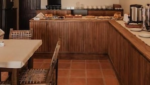 Een keuken met een houten kookeiland, hangende hanglampen en een betegelde vloer.