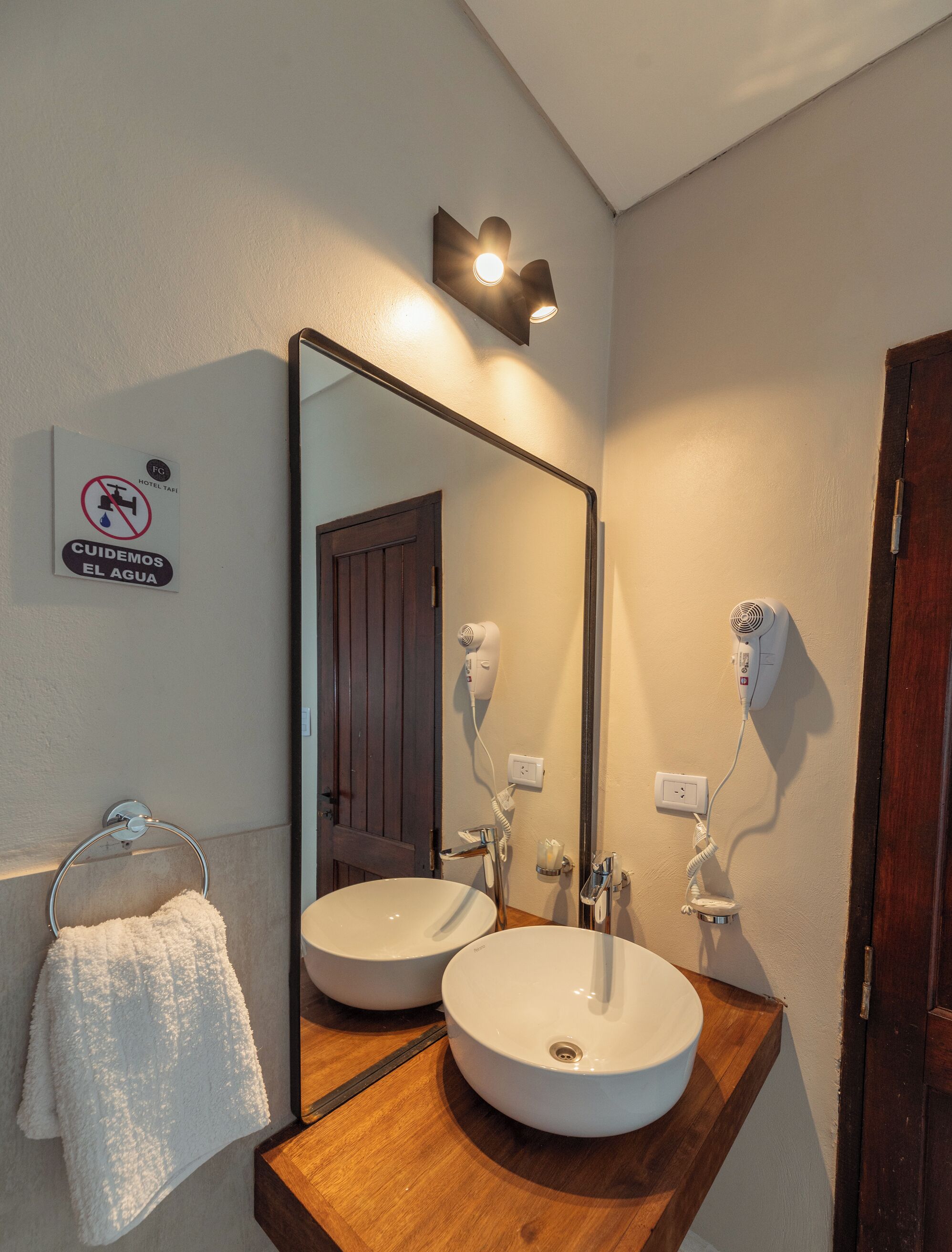 A bathroom with two sinks, a towel rack, a mirror, and a sign indicating no water fountains.