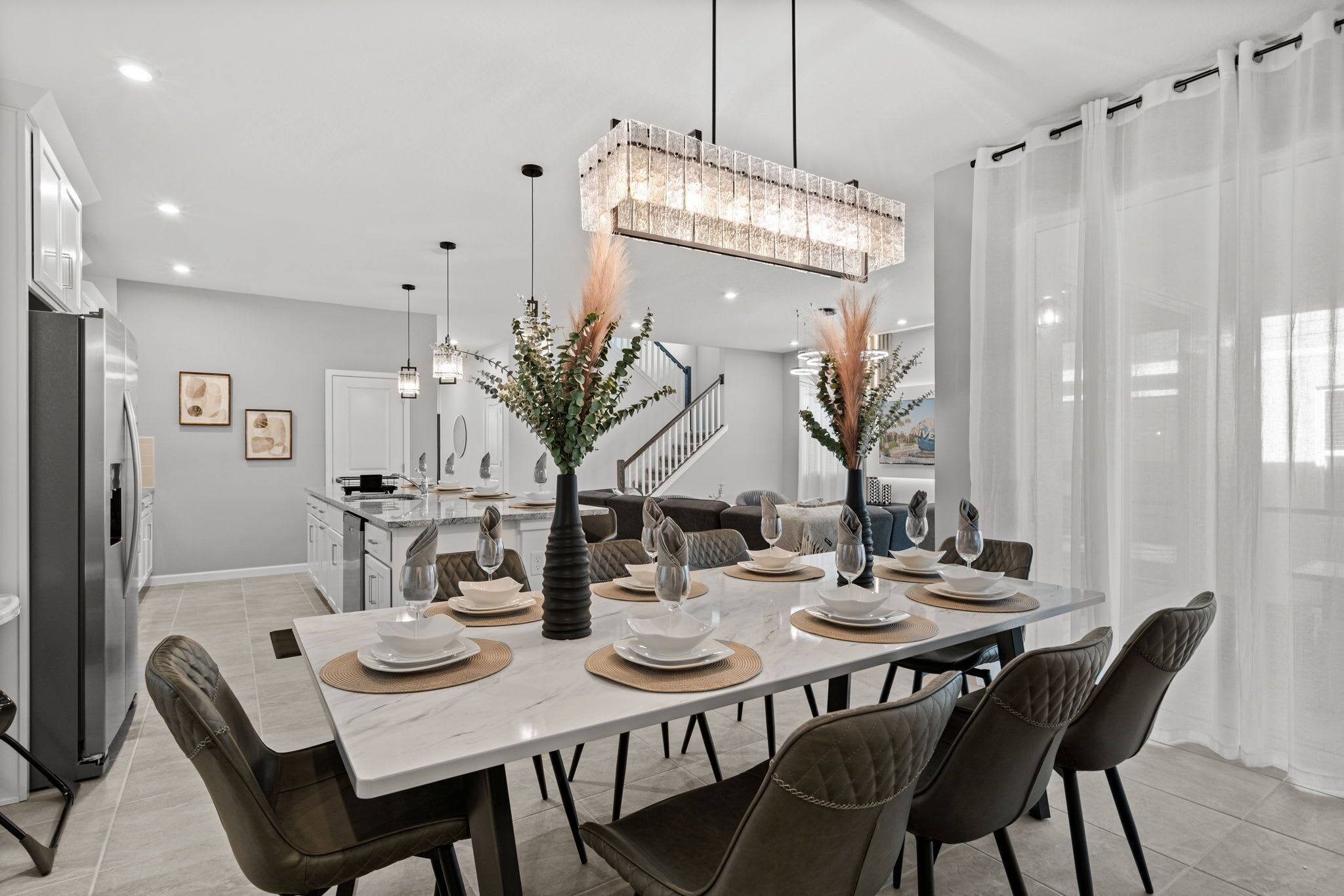 Un espace repas moderne avec une table en marbre dressée pour six personnes, entourée de fauteuils en cuir.