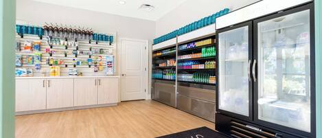 A modern retail space with shelves stocked with various products, a refrigerated display case, and a door leading to another area.