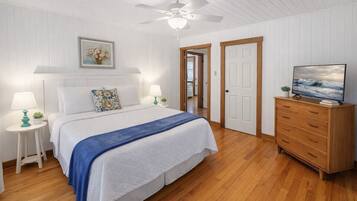 A bedroom with a bed, a dresser, a television, and a ceiling fan.