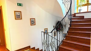 Una escalera con barandillas de metal decorativas y un tapete estampado en la parte inferior.