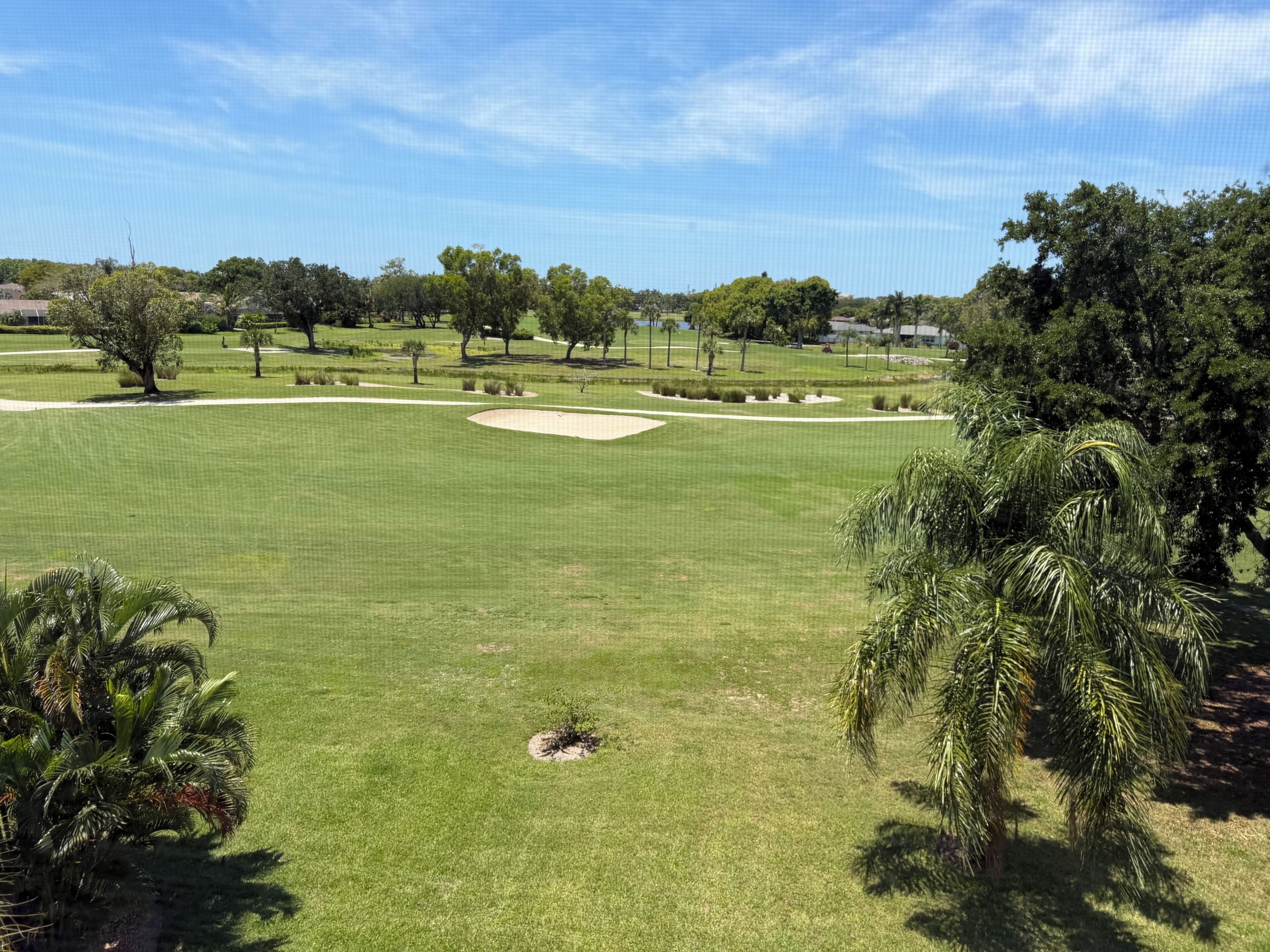 A golf course with sand bunkers, trees, and a clear sky.