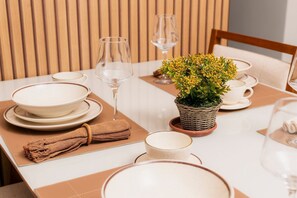 A dining table set with plates, bowls, and a small potted plant.