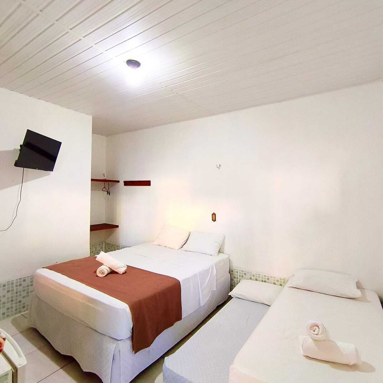Una habitación de hotel con una cama, un televisor montado en la pared y una mesita de noche.