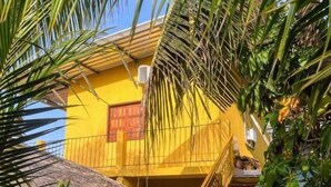 A yellow building with a staircase and a thatched roof structure. - Pousada Flora (Santarém)