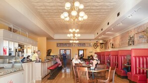Ein Restaurantinnenraum mit Holzböden, roten Sitzbänken und einem zentralen Kronleuchter.