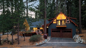 A cabin with a garage, a deck, and a staircase leading to the upper level. - Retreat With Lake Access, Deck & Modern Interior Agate Peak by Avantstay (Carnelian Bay)