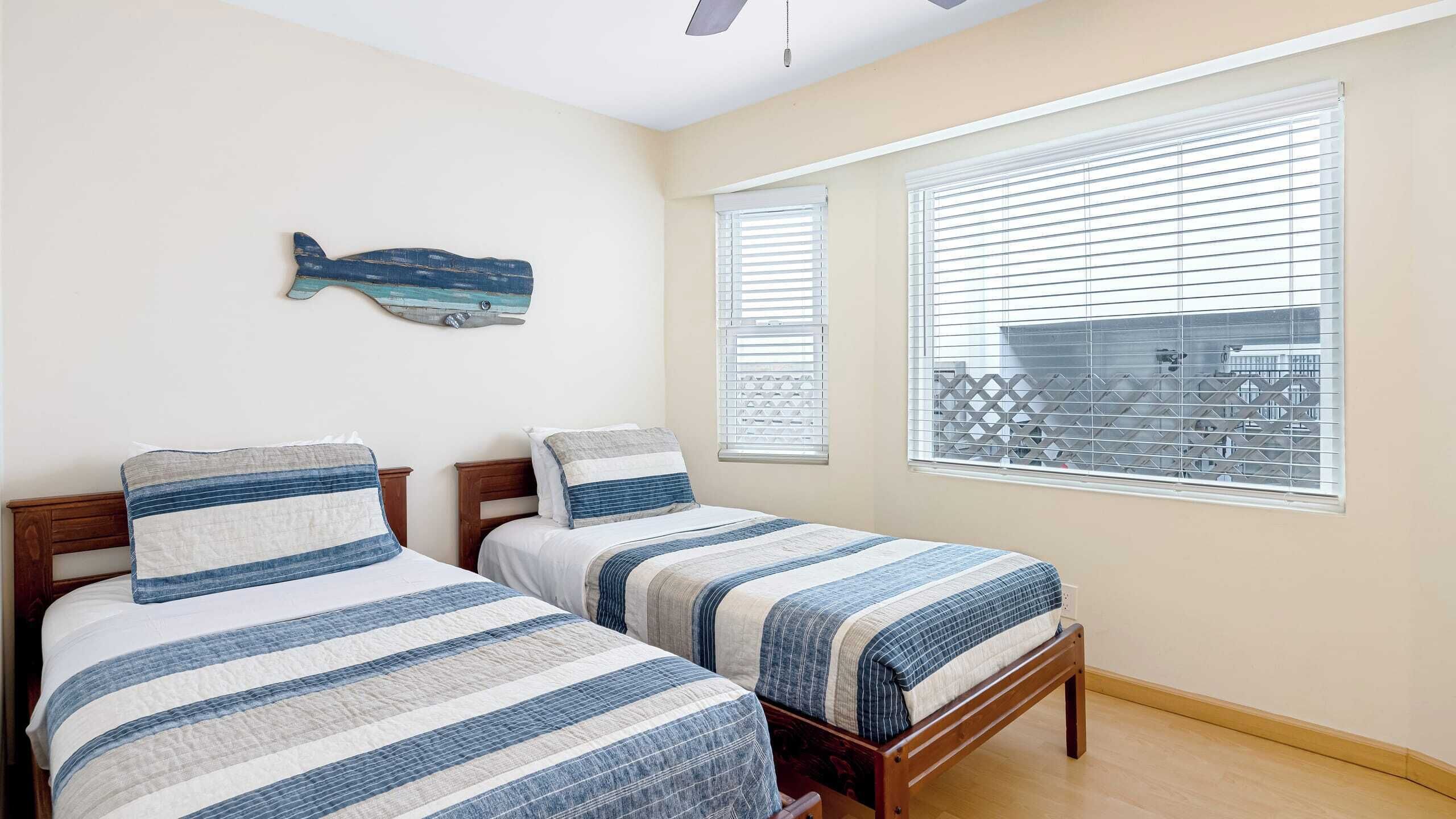 Ein Schlafzimmer mit zwei Betten, einem Deckenventilator und einem Wandbild mit Fischmotiven.