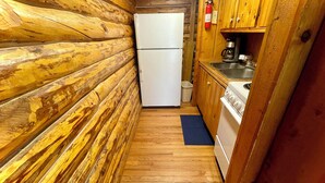 Cocina rústica de madera con refrigerador blanco, estufa y lavabo.