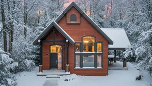 Eine Holzhütte mit dunkelbrauner Fassade, einer Veranda und einem überdachten Sitzbereich im Freien.